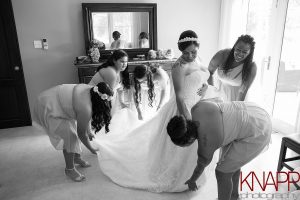 Bridesmaids making last minute arranging of wedding dress.