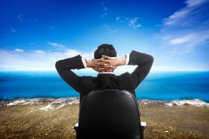 Executive in a desk chair looking out over the ocean.