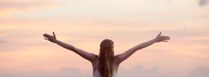 Woman with her arms spread out in front of the ocean