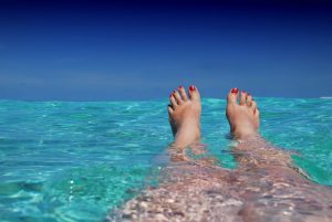 Woman with feet sticking out of the ocean.