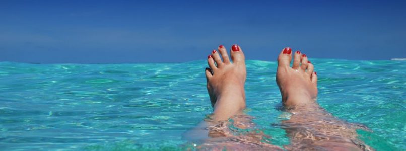 Woman with feet sticking out of the ocean.