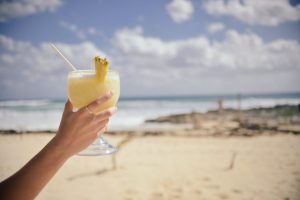 Woman holding a mixed drink at the beach.