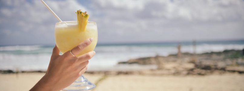 Woman holding a mixed drink at the beach.