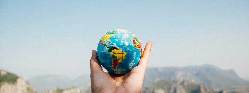 Person holding a small globe with mtns in background