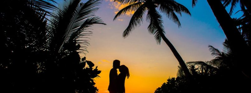 Couple Kissing in front of a tropical sunset