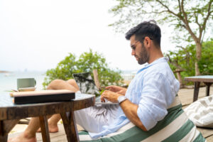 Businessman working on laptop at tropical island on summer holiday vacation.