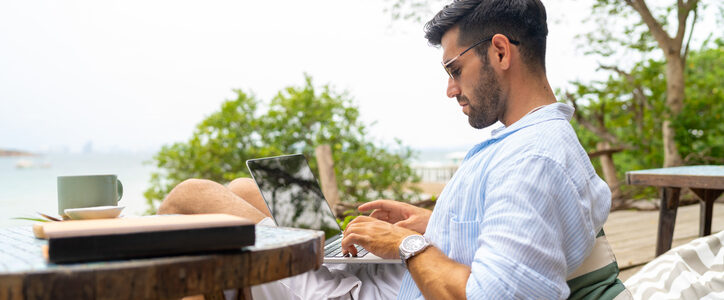 Businessman working on laptop at tropical island on summer holiday vacation.