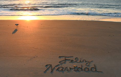 Feliz Navidad written in sand at beach