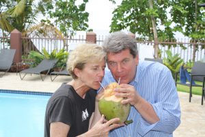 Man and woman drinking from a coconut poolside Maria's Villa.