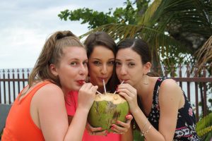 Three women drinking from a coconut poolside Maria's Villa PR