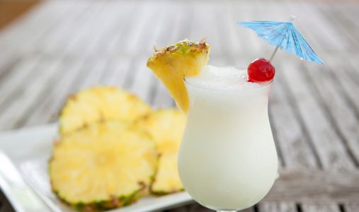 Pina colada on a table with pineapple slices.